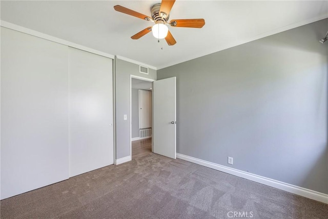 unfurnished bedroom featuring carpet floors, a closet, ceiling fan, ornamental molding, and baseboards