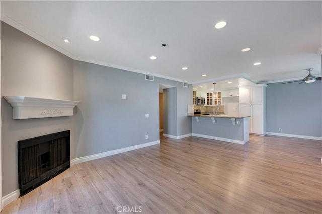 unfurnished living room with ornamental molding, recessed lighting, ceiling fan, a sink, and baseboards