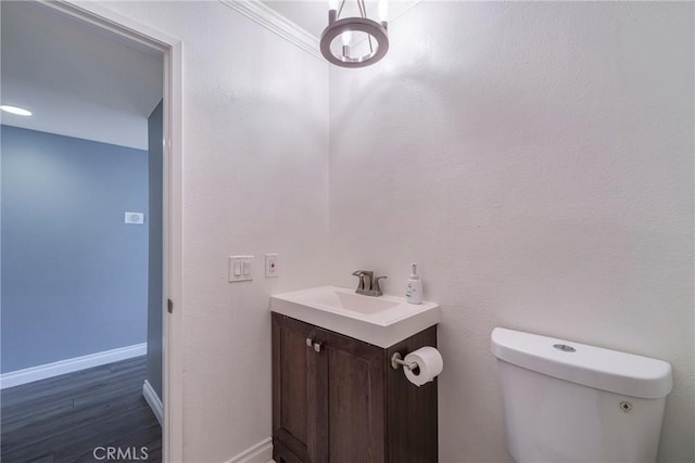 bathroom with toilet, wood finished floors, baseboards, and vanity