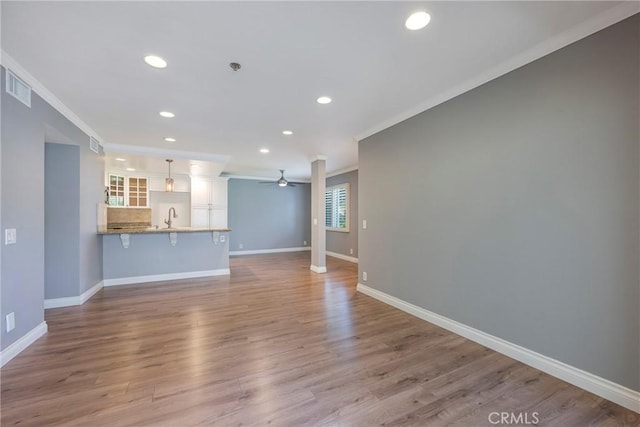 unfurnished living room with crown molding, ceiling fan, recessed lighting, baseboards, and a sink