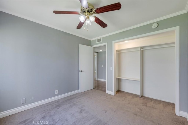 unfurnished bedroom featuring carpet floors, crown molding, baseboards, ceiling fan, and a closet