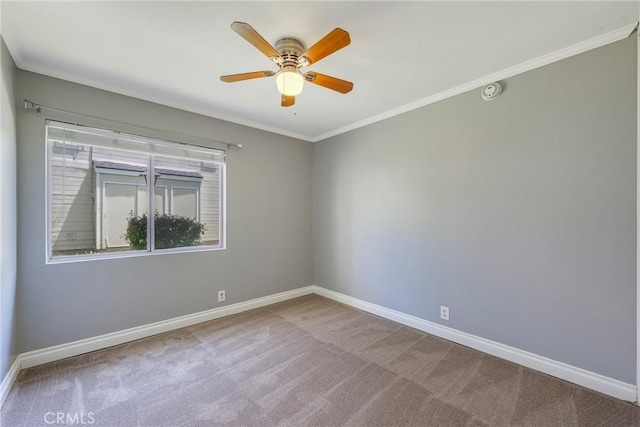 carpeted spare room featuring baseboards, a ceiling fan, and crown molding