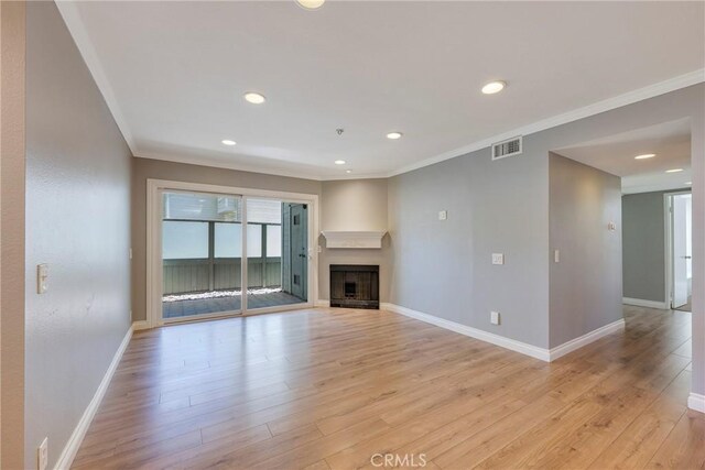unfurnished living room featuring ornamental molding, light wood-style floors, baseboards, recessed lighting, and a fireplace