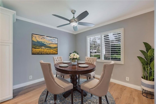 dining room featuring light wood-style flooring, baseboards, a ceiling fan, and ornamental molding