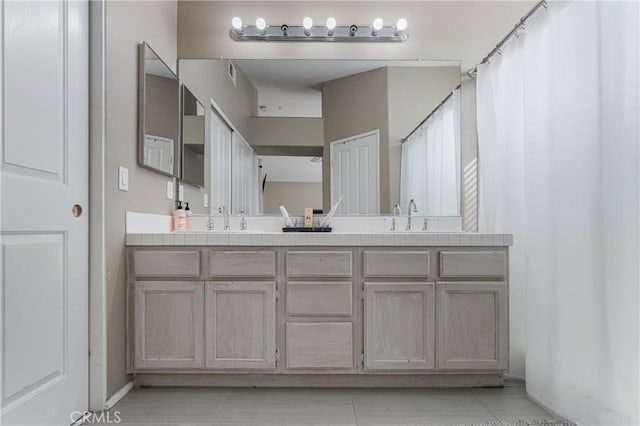 bathroom with double vanity, a sink, and tile patterned flooring