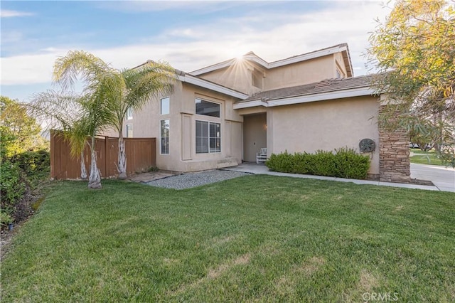 view of front of home featuring fence, stucco siding, and a front yard