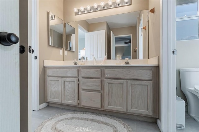 full bath featuring tile patterned flooring, double vanity, toilet, baseboards, and a sink