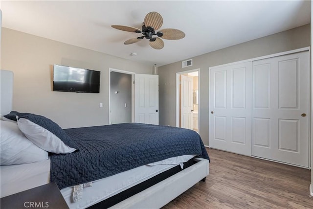 bedroom featuring ceiling fan, wood finished floors, ensuite bathroom, visible vents, and a closet