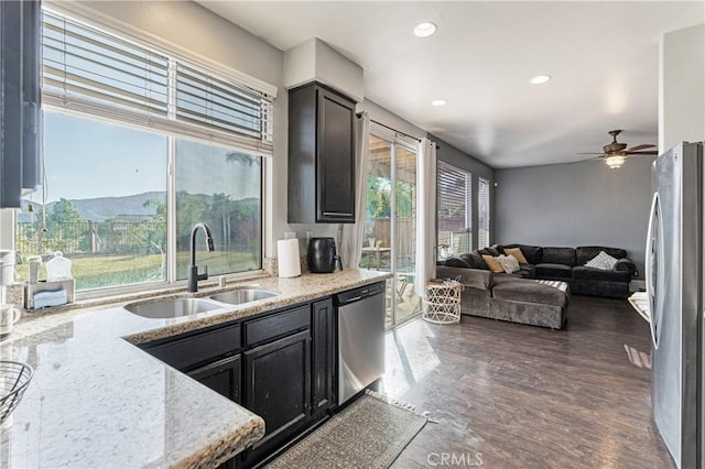 kitchen featuring a ceiling fan, a sink, light stone counters, stainless steel appliances, and recessed lighting