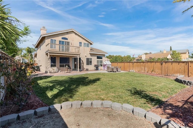 rear view of house with a fenced backyard, a balcony, and a patio area