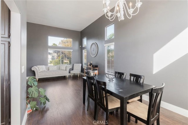 dining area featuring baseboards, an inviting chandelier, wood finished floors, and a high ceiling
