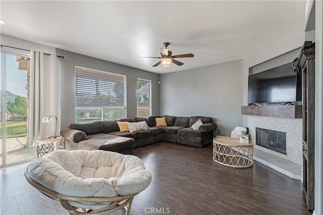 living room with ceiling fan, dark wood finished floors, and a glass covered fireplace