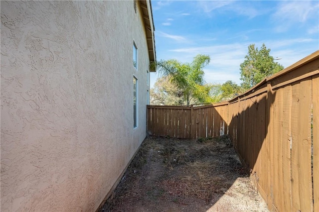 view of side of home with stucco siding and fence