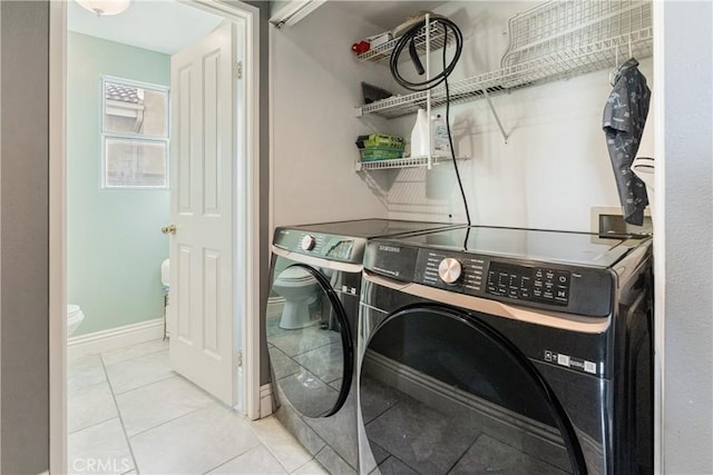 laundry room featuring laundry area, washer and clothes dryer, baseboards, and tile patterned floors