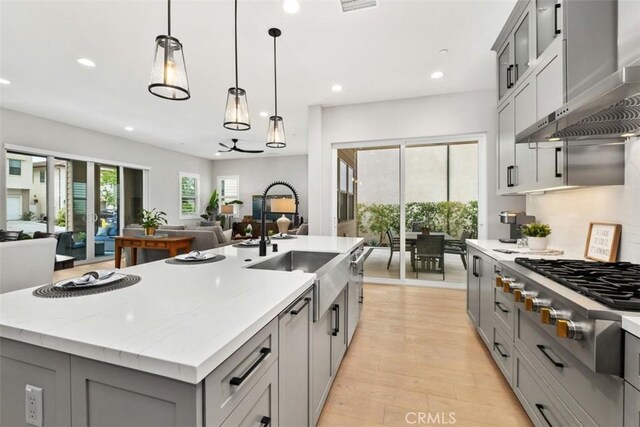 297 Sawbuck, Irvine, CA 92618 - kitchen featuring gray cabinetry, stainless steel gas stovetop, open floor plan, wall chimney range hood, and a sink