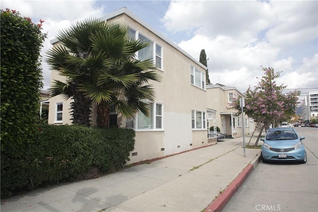 view of property exterior with stucco siding and crawl space