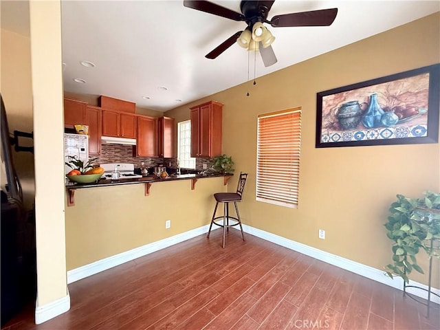 7163 Watcher St, Commerce, CA 90040 - kitchen featuring white gas stove, under cabinet range hood, dark countertops, a kitchen bar, and recessed lighting