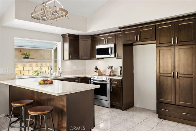 5222 Auburn Cir, Westminster, CA 92683 - kitchen featuring a breakfast bar area, dark brown cabinetry, appliances with stainless steel finishes, a sink, and light tile patterned floors