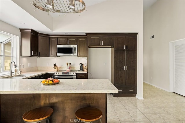 5222 Auburn Cir, Westminster, CA 92683 - kitchen with appliances with stainless steel finishes, dark brown cabinets, a sink, high vaulted ceiling, and a peninsula