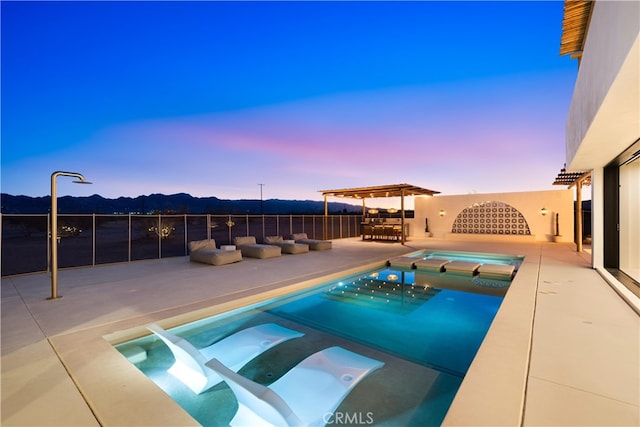 63973 Gold Nugget Rd, Joshua Tree, CA 92252 - pool at dusk featuring a pool with connected hot tub, a mountain view, and a patio area