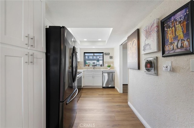 12812 Timber Rd Unit 22, Garden Grove, CA 92840 - kitchen with freestanding refrigerator, dishwasher, light countertops, light wood-style floors, and white cabinets
