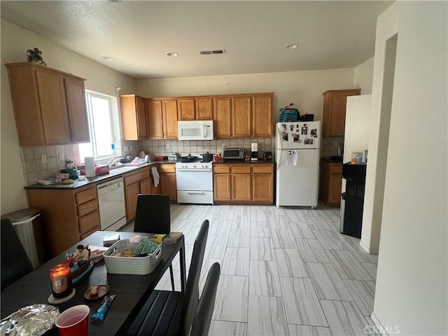 938 Sparrow Way, Perris, CA 92571 - kitchen with brown cabinetry, a sink, decorative backsplash, and white appliances