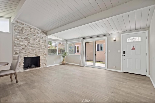 unfurnished living room featuring vaulted ceiling with beams, baseboards, a fireplace, and light wood-type flooring