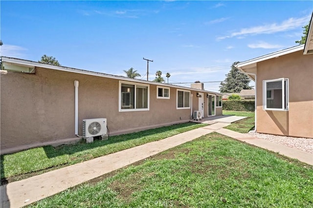 view of front of home with stucco siding, a chimney, ac unit, and a front lawn
