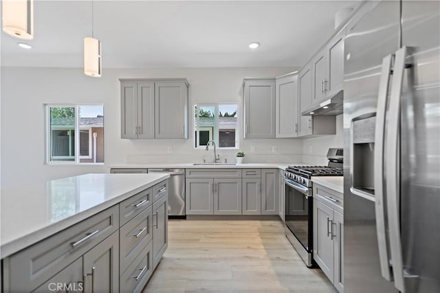 kitchen featuring recessed lighting, under cabinet range hood, a sink, gray cabinetry, and stainless steel appliances
