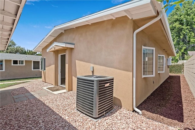 back of house with fence, stucco siding, and cooling unit