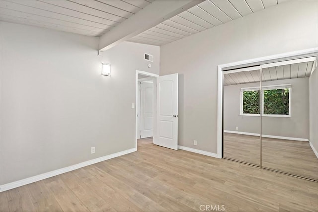 unfurnished bedroom with vaulted ceiling with beams, baseboards, wood finished floors, and visible vents