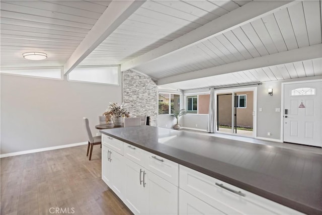 kitchen featuring white cabinets, baseboards, dark countertops, and vaulted ceiling with beams