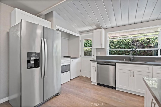 kitchen with lofted ceiling, washer and clothes dryer, white cabinetry, a sink, and appliances with stainless steel finishes
