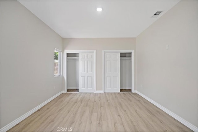 unfurnished bedroom with visible vents, light wood-type flooring, baseboards, multiple closets, and recessed lighting