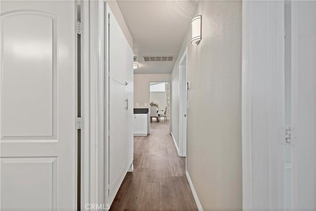 hall with baseboards, dark wood-style floors, and visible vents