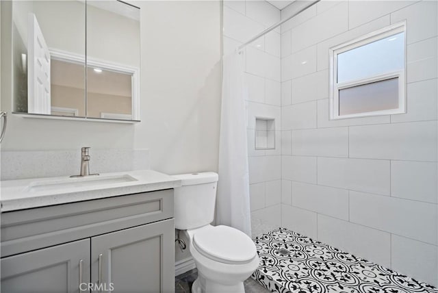 full bathroom featuring vanity, a tile shower, and toilet