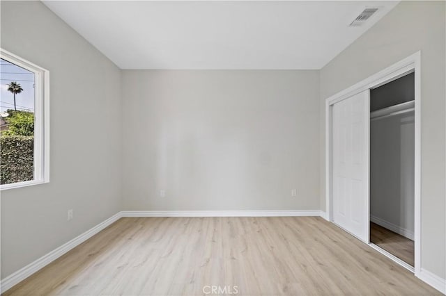 unfurnished bedroom with light wood-type flooring, baseboards, visible vents, and a closet