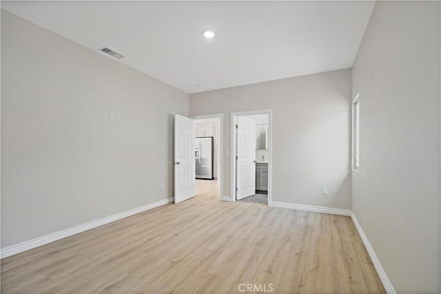 unfurnished bedroom with baseboards, visible vents, stainless steel fridge, and light wood-style floors