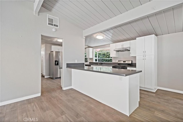 kitchen with visible vents, dark countertops, baseboards, under cabinet range hood, and appliances with stainless steel finishes
