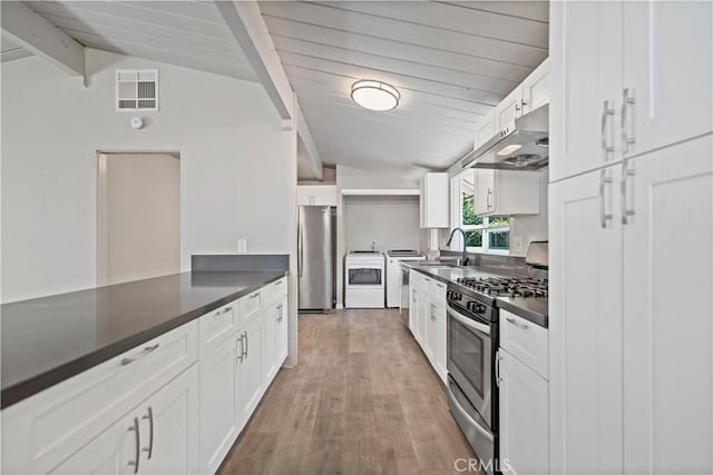 kitchen featuring dark countertops, appliances with stainless steel finishes, under cabinet range hood, and visible vents
