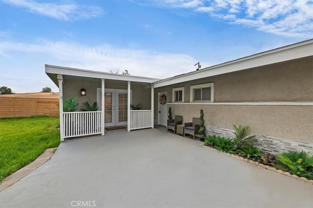 exterior space with stucco siding, a yard, fence, and french doors