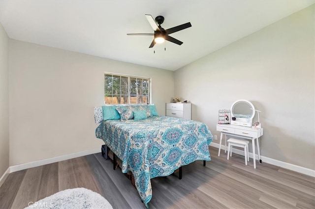 bedroom with baseboards, ceiling fan, vaulted ceiling, and wood finished floors