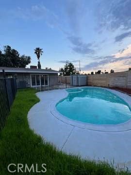 pool at dusk with a fenced backyard, a fenced in pool, and a patio