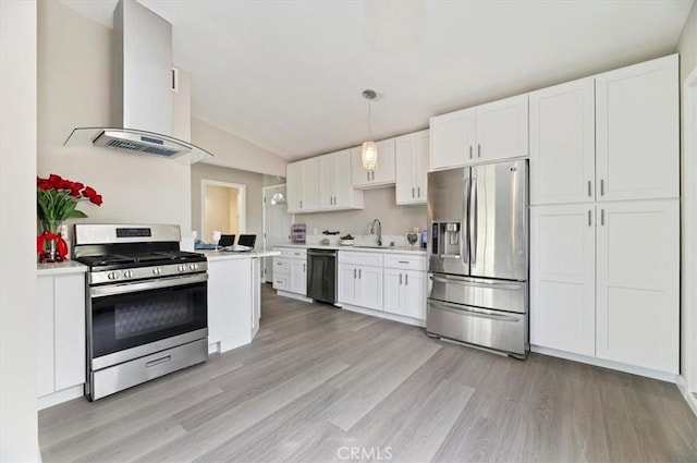 kitchen featuring wall chimney range hood, light countertops, a sink, light wood finished floors, and appliances with stainless steel finishes