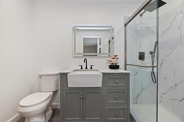 bathroom featuring baseboards, a marble finish shower, toilet, and vanity