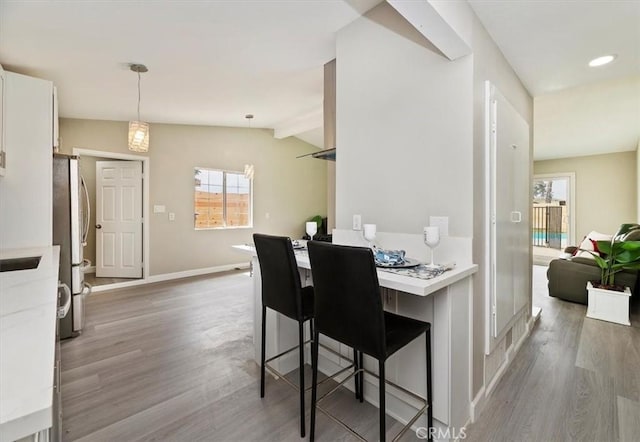 dining space with baseboards, wood finished floors, and lofted ceiling