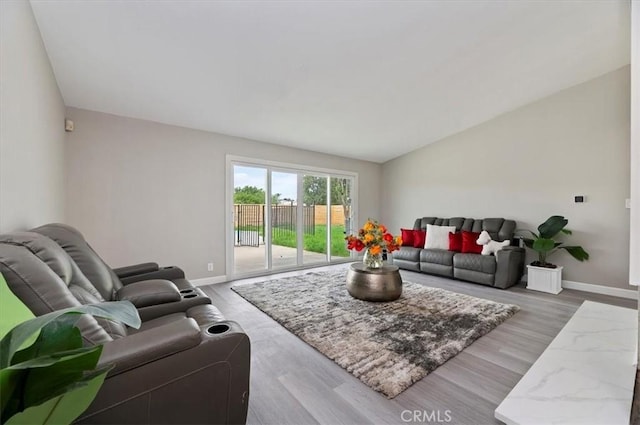 living room featuring baseboards, vaulted ceiling, and wood finished floors