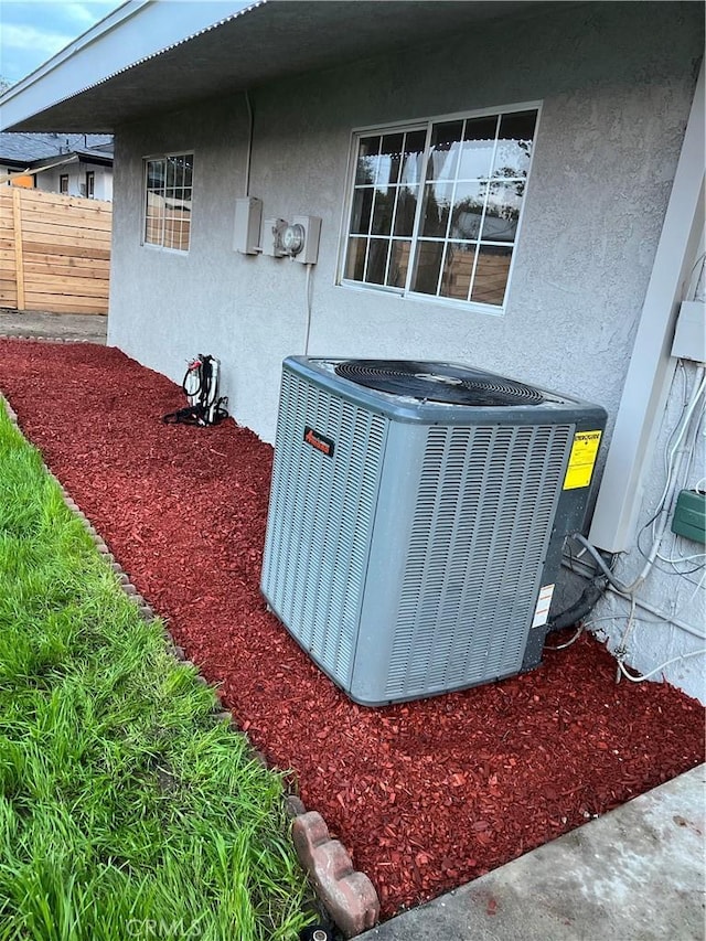 exterior details featuring stucco siding, electric meter, central air condition unit, and fence