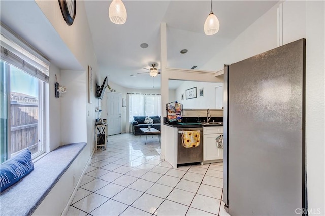kitchen featuring dark countertops, white cabinets, a sink, light tile patterned floors, and stainless steel appliances