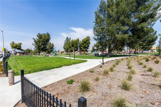 view of home's community featuring a yard, fence, and playground community